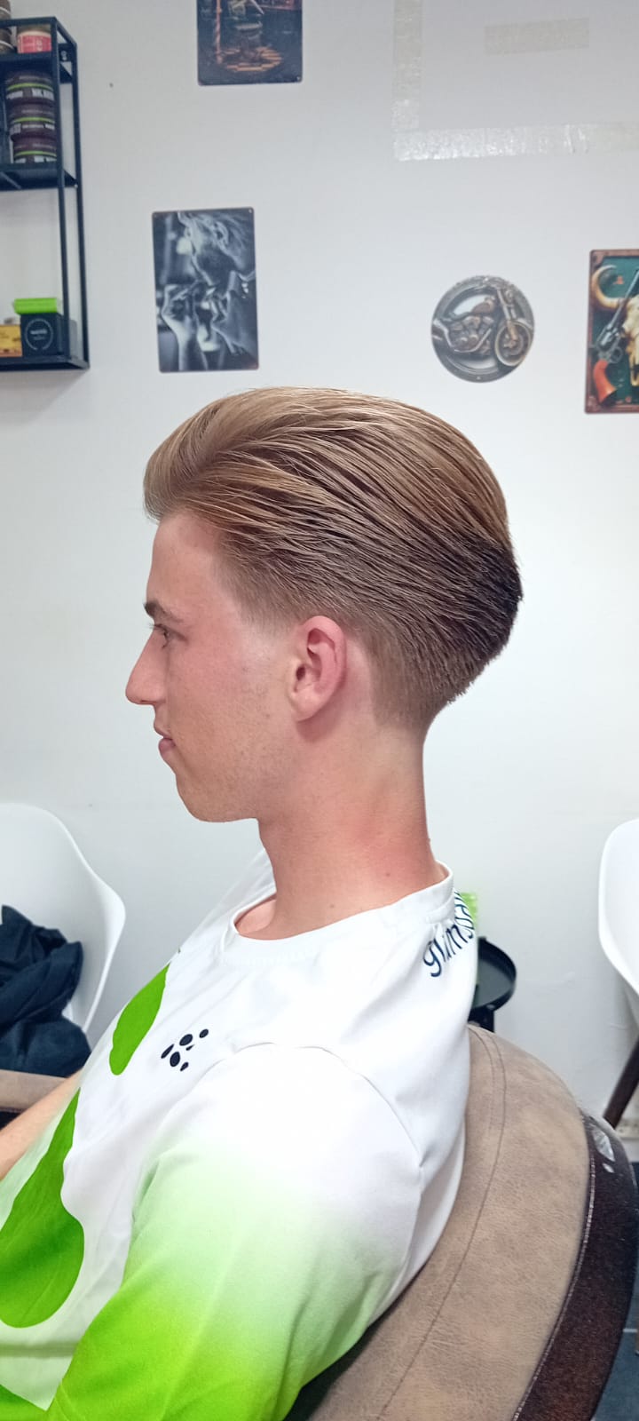 Slick back frisure med low fade i siderne på klient med blondt hår - herrefrisure set fra venstre