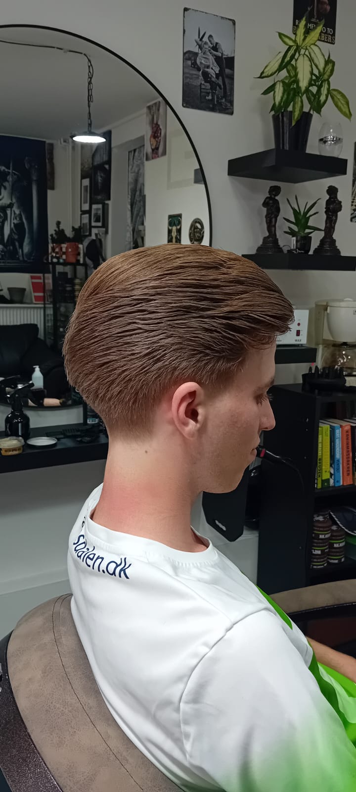 Slick back frisure med low fade i siderne på klient med blondt hår - herrefrisure set fra højre